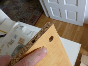 Missing holes tend to slow the assembly process - that dime-sized hole at the end of my finger ought to be connected to a smaller diameter hole through the edge of the particle board for the cam lock bolt, but isn't.