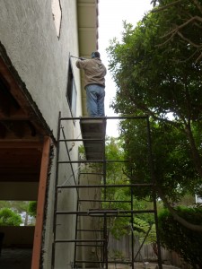 Super Hombre chipping off even more stucco atop an unsafe perch.