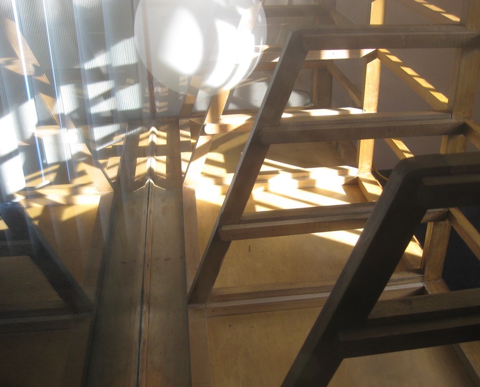 Light streaming through the workshop blinds, casting shadows across wooden frames and the globe lamp